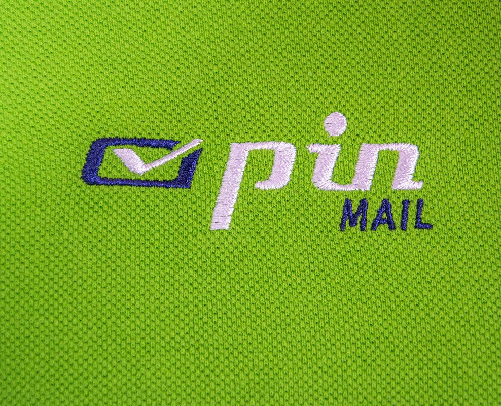 Gesticktes PIN MAIL AG Logo auf grünem Textil