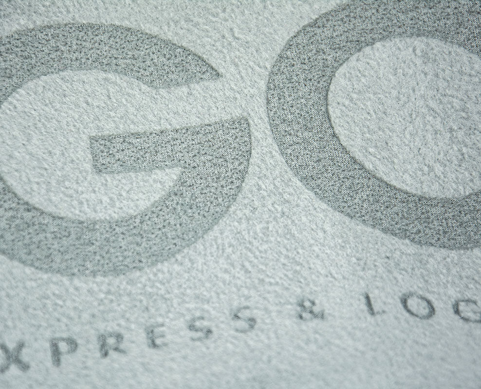 Laser-Veredelung vom GO! Logo auf grauem Textil